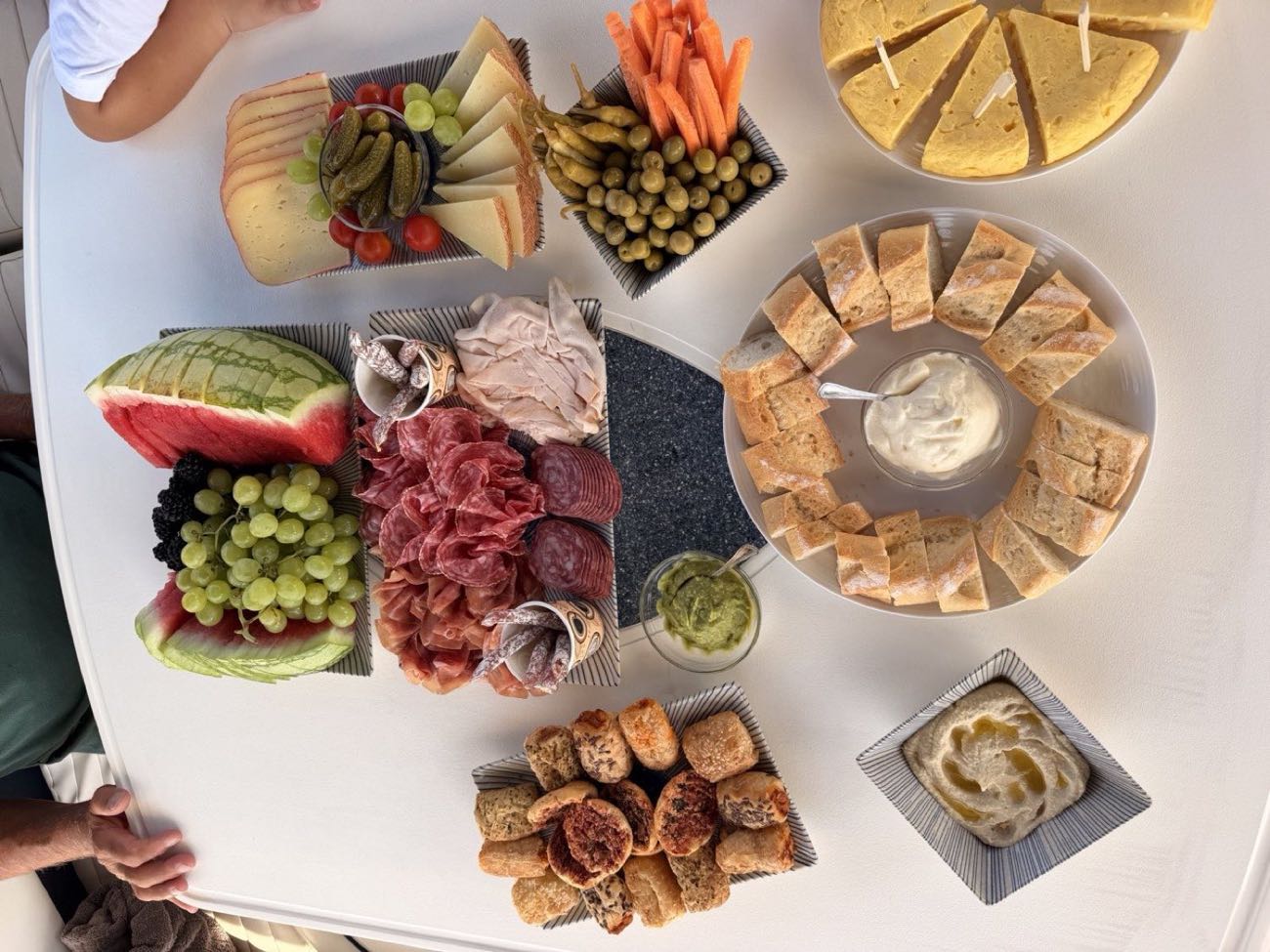 Tabla de tapas con fruta, jamón, queso y pan servida a bordo